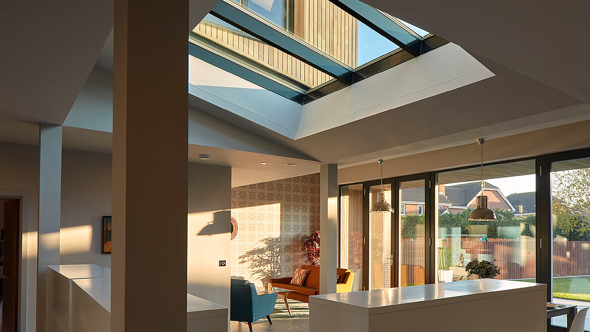 Modernes Wohnhaus mit großzügigem Glasdach und viel Tageslichteinfall im Wohnbereich.