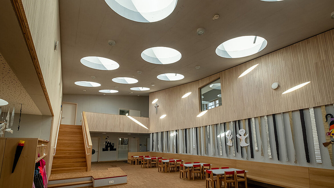 Salle polyvalente du jardin d'enfants St. Severin à Garching avec des fenêtres rondes de toit plat